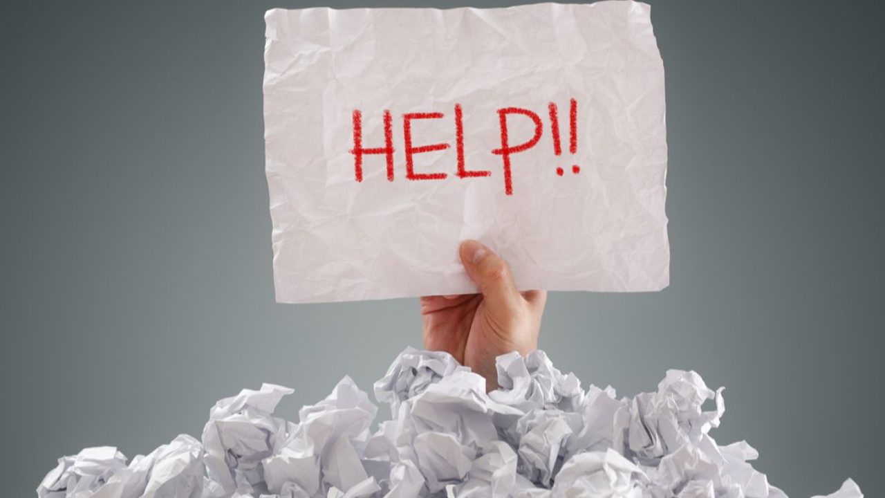 hand holding a paper with the word help in the middle of crumpled paper